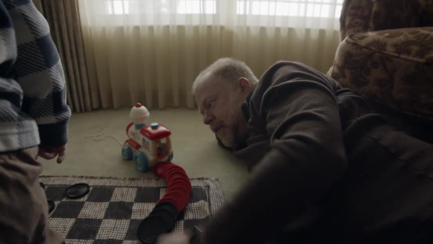 Grandfather and grandson are playing with toys on living room floor