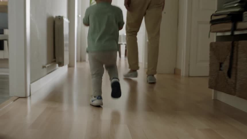Man and toddler walk down a hallway