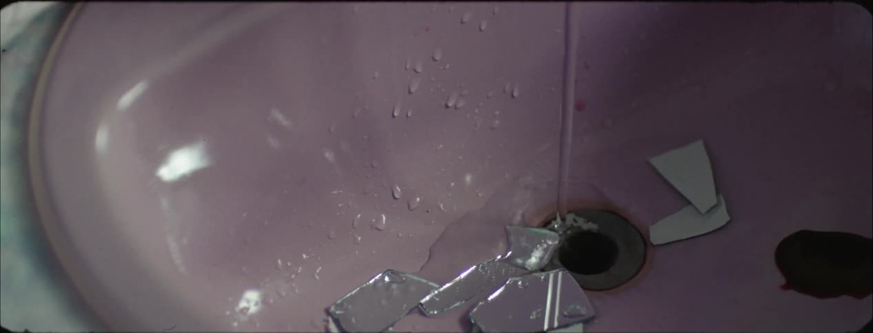 Water drains into a sink as broken glass and blood fall into it