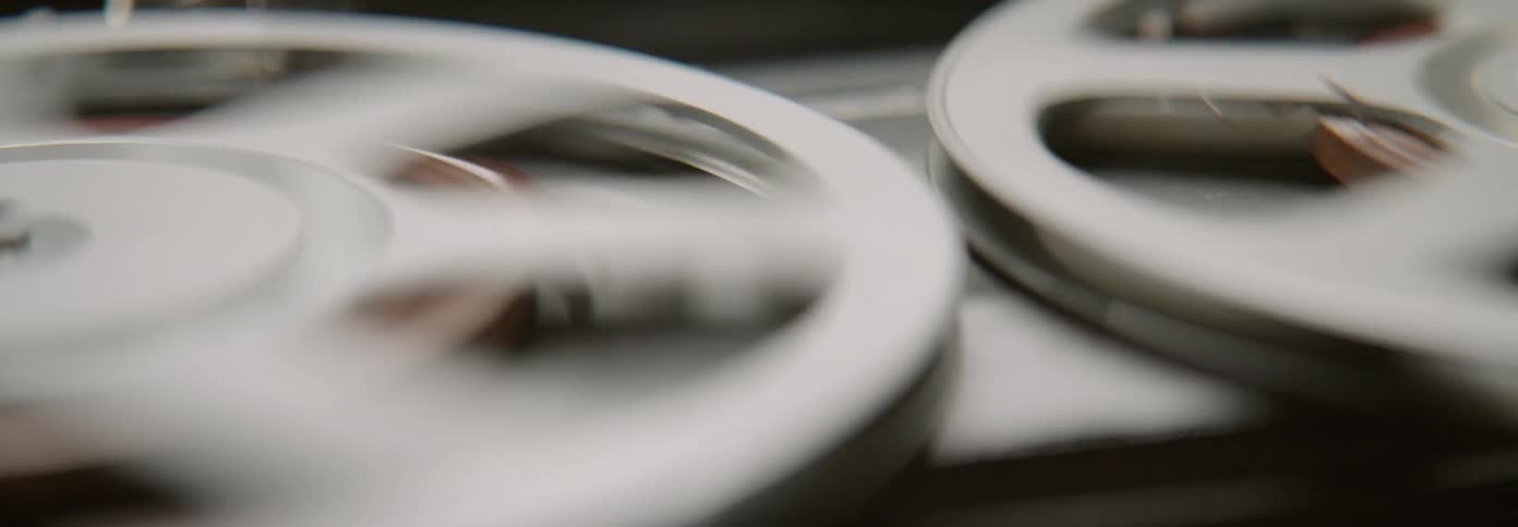 Tape deck reels are spinning to a stop inside in daylight