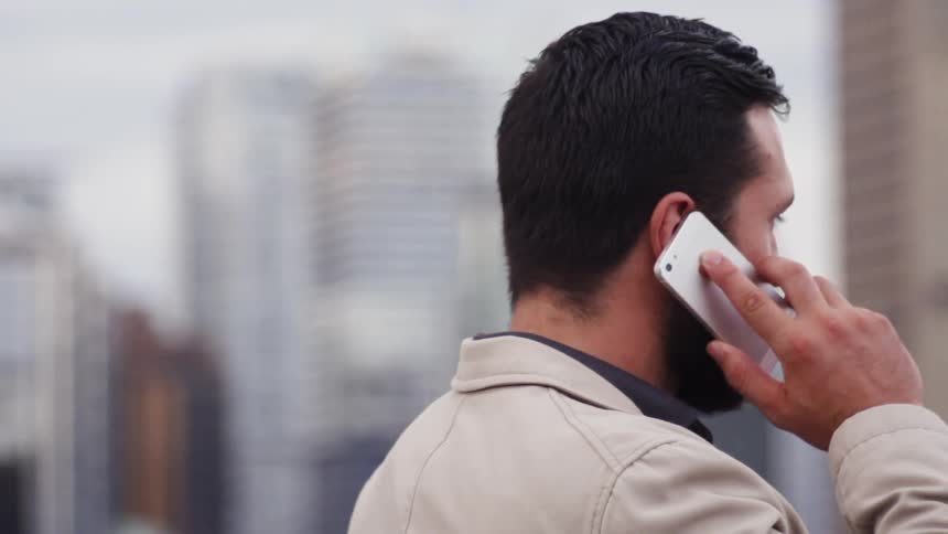 A man stands outside using his cell phone