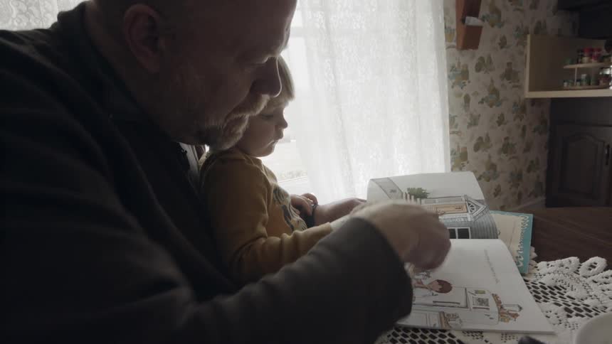 An elderly man reads to a young child
