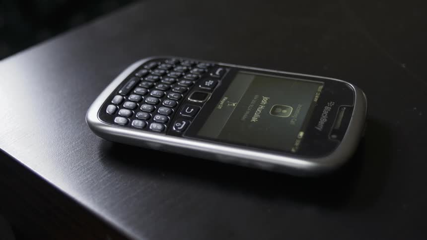 Hand picks up a cellphone from a table after its screen activates