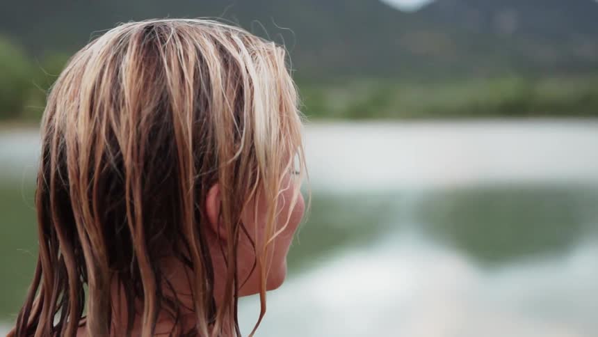 Woman looks outside across a pond