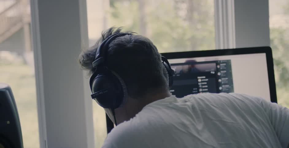 A man uses headphones at a computer