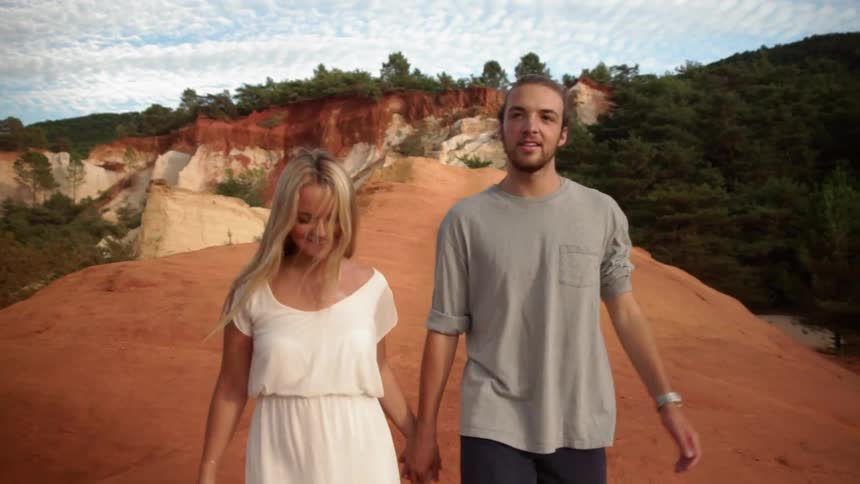 A couple holds hands as they walk on a ridge