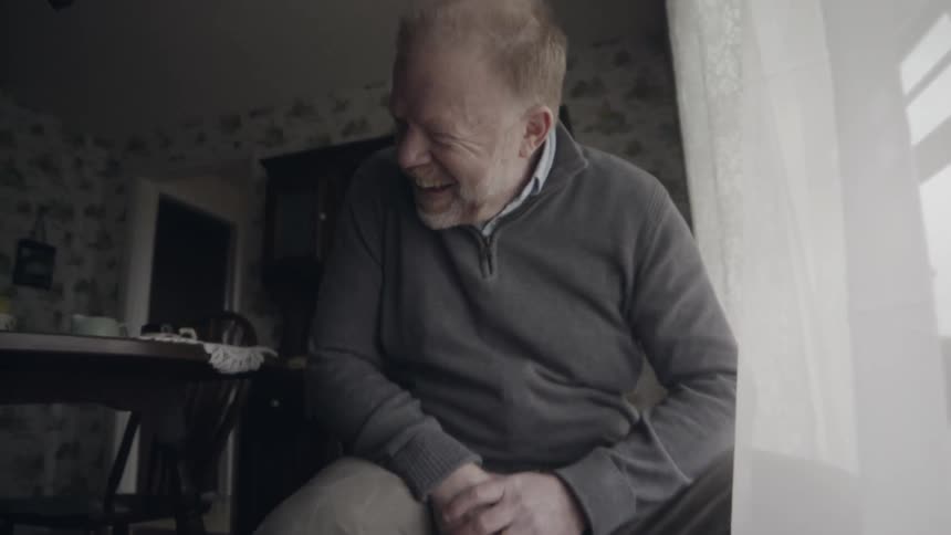 Man smiles while watching a toddler boy play