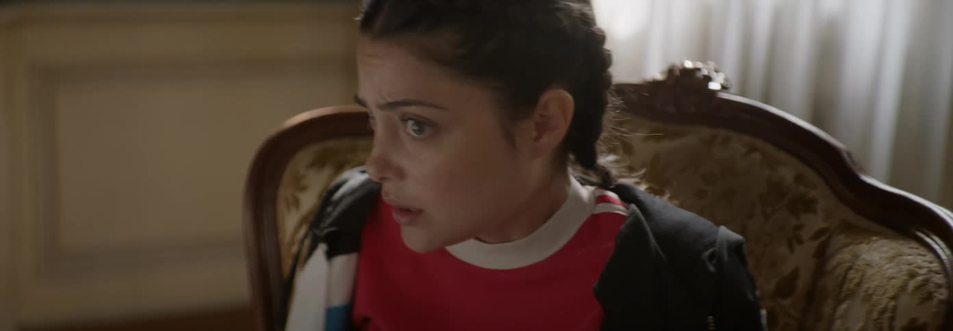 A teenage girl is looking scared as she bolts from a chair inside a room in daylight