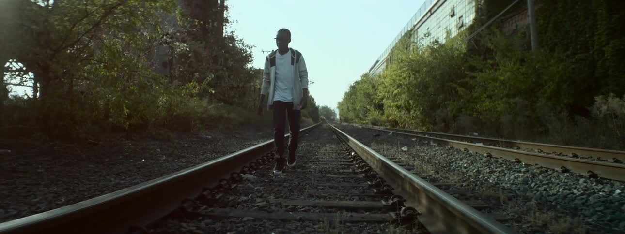 A young man walking down abandoned railroad tracks