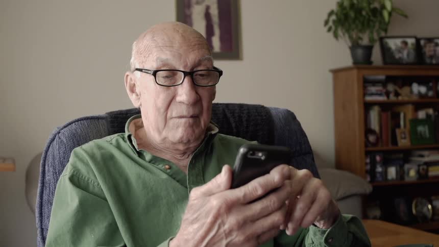 An elderly man uses a cell phone
