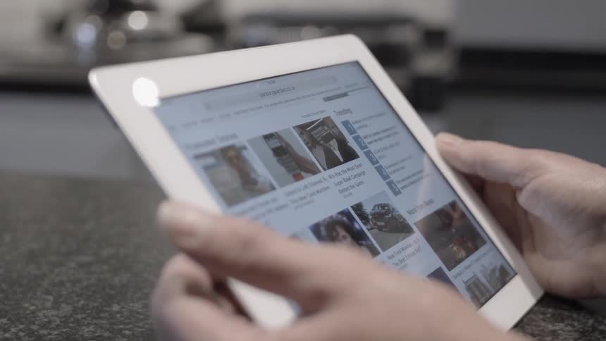 A person is using tablet inside a kitchen in daylight