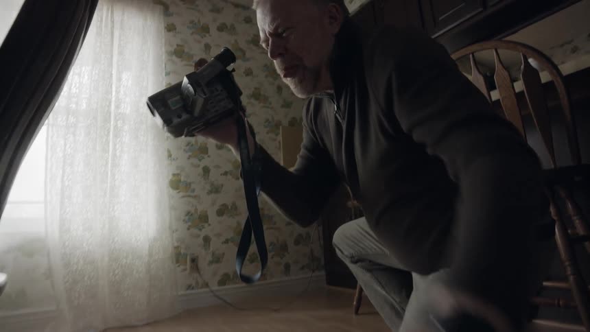 Elderly man records a toddler crawling on the dining room floor