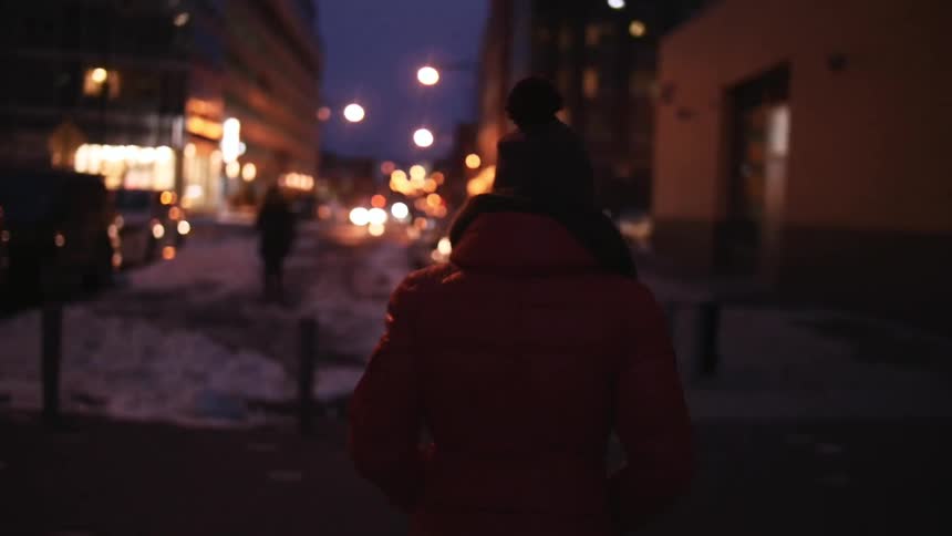 Person walking along a sidewalk at night