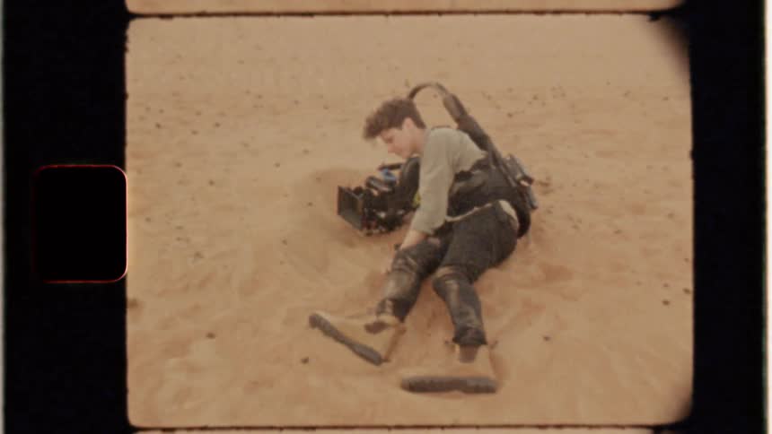 Man lies in sand with a video camera