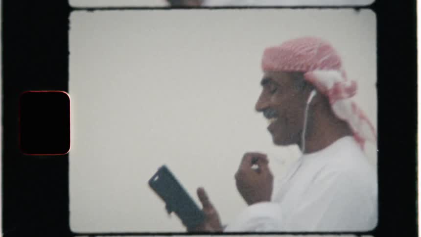 A middle eastern man uses a phone outside