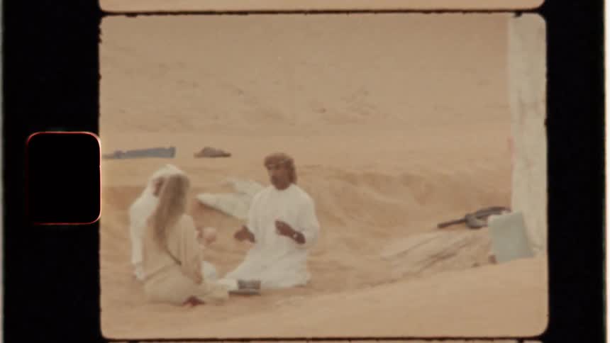 Men and a woman sit outside a tent in the desert
