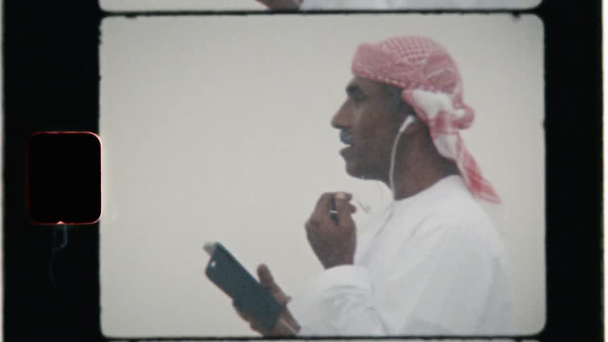 A middle eastern man uses a phone outside