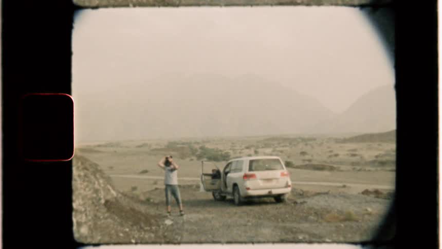 A woman stands outside of their parked car