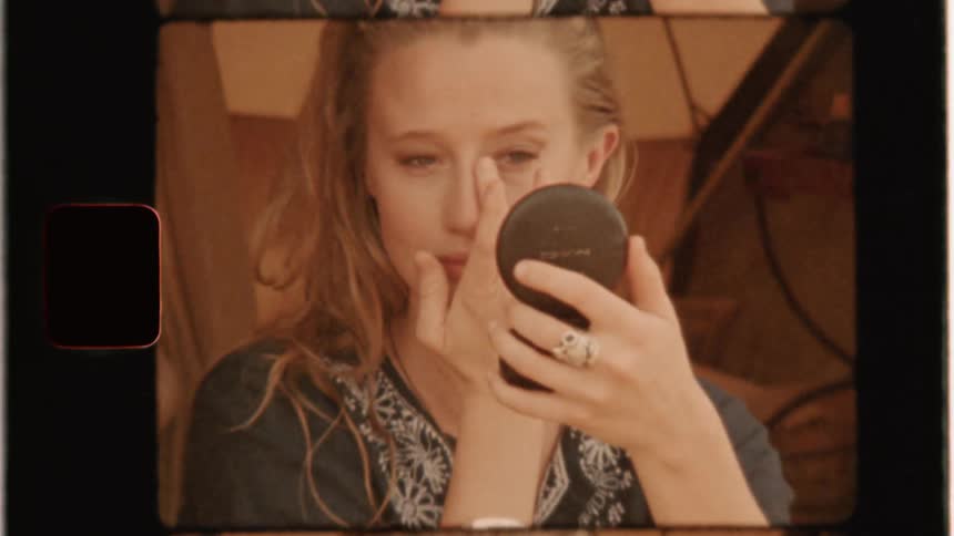 A woman applies makeup with a small mirror