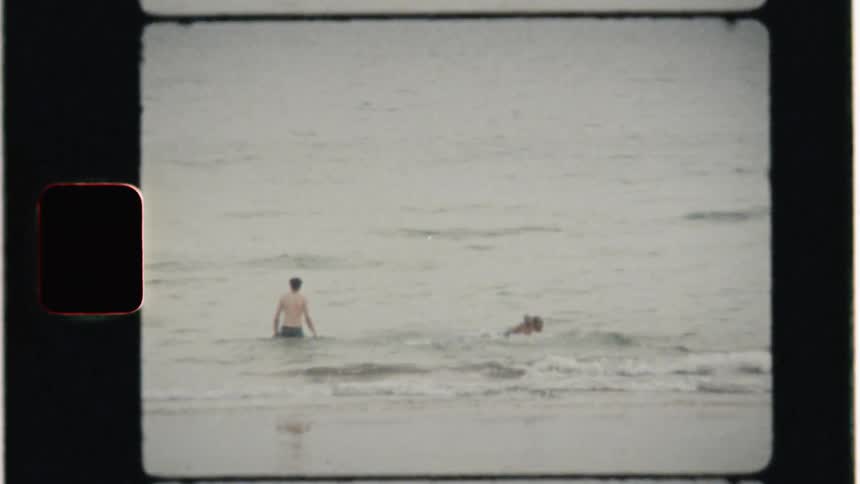 Two people walk and swim in the ocean