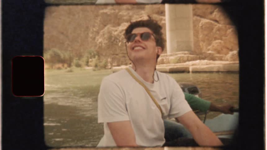 Two men ride on a boat down a river