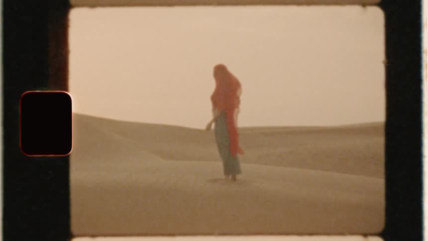 Woman in a red veil stands in a desert
