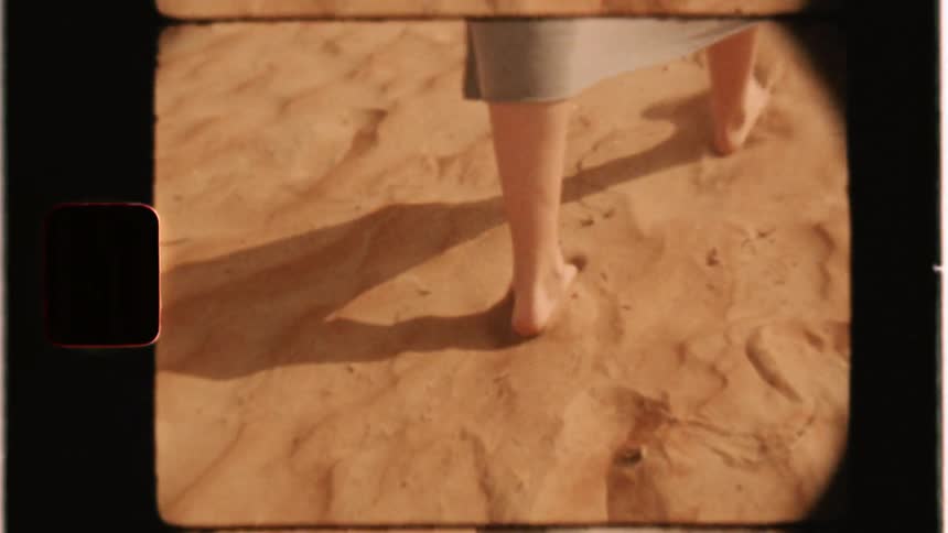 A woman walks barefoot in the sand