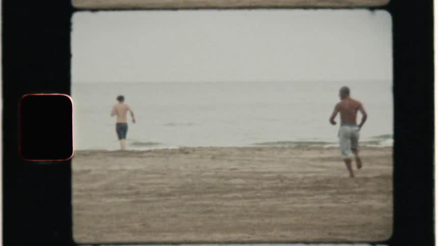 Shirtless men run on a beach