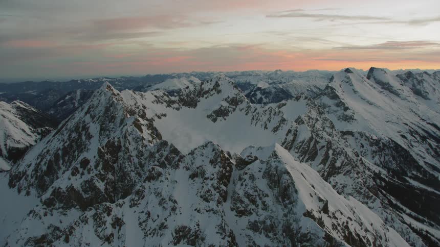 The sun sets over snowy mountains