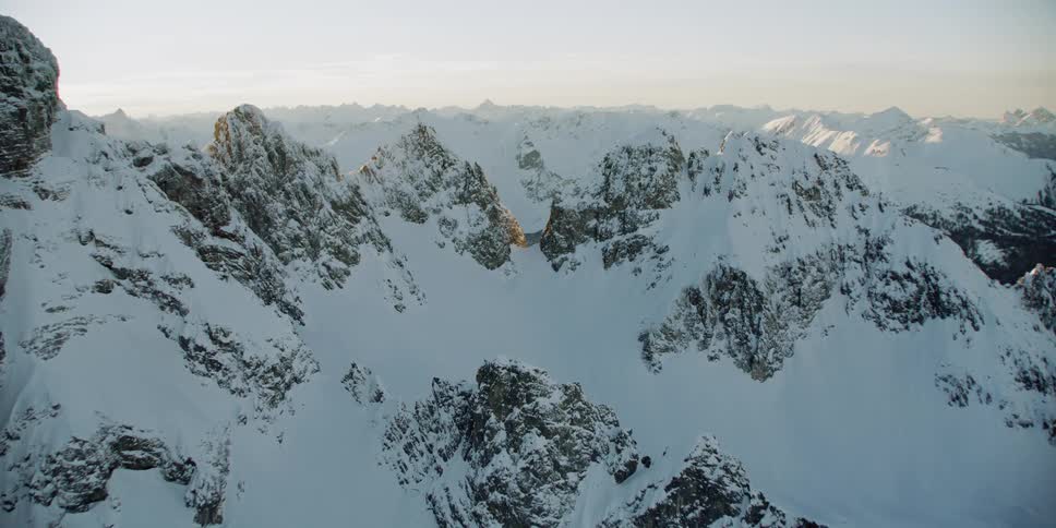 Snow is covering the slopes of a mountain range during the day