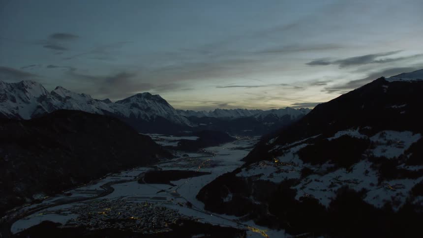 Snow covered hills sit under a cloudy sky