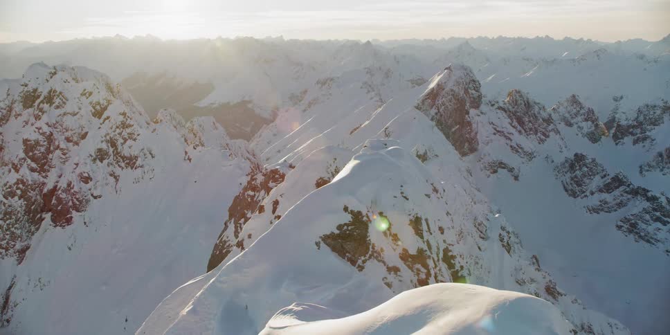 The sun sets over snowy mountains