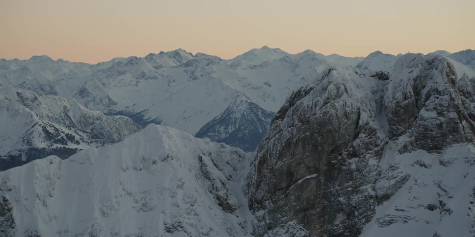 The sun sets over snowy mountains