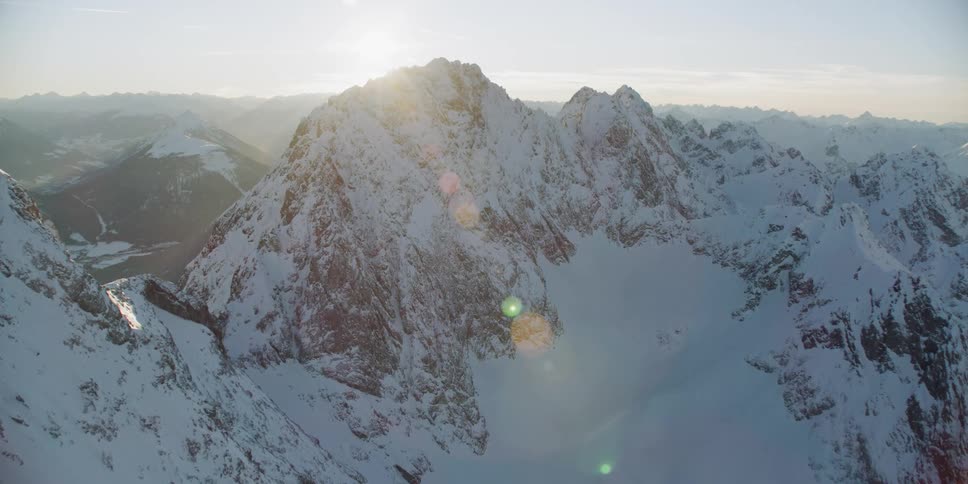 The sun sets behind snowy mountains
