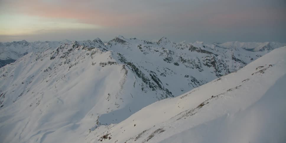 The sun sets over snowy mountains