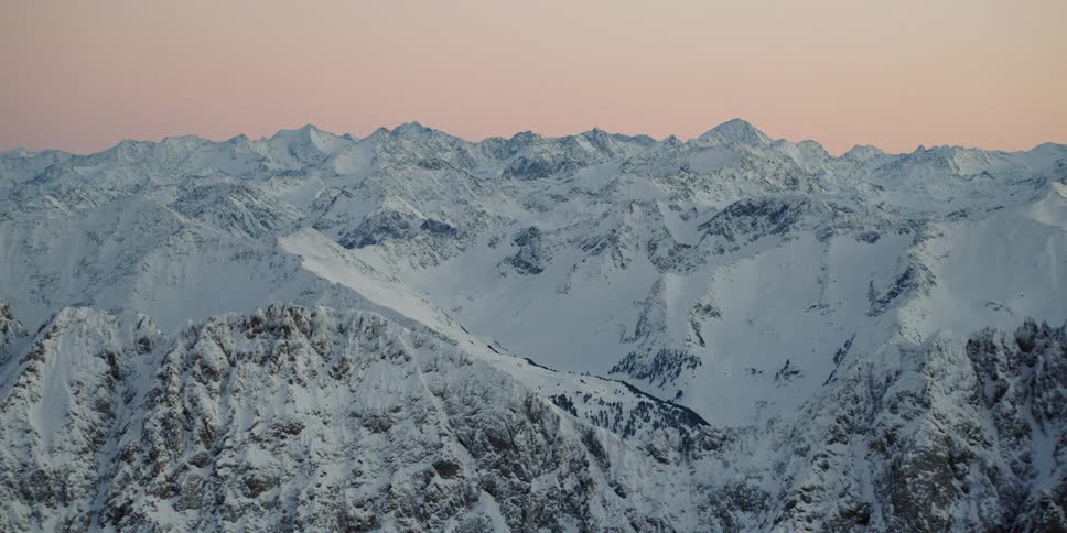 The sun sets over snowy mountains