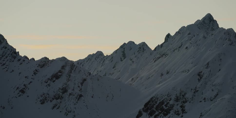 The sun sets over snowy mountains