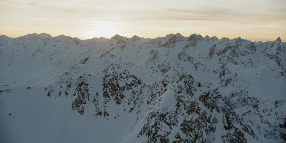 Dawn is breaking over a snow-covered mountain range