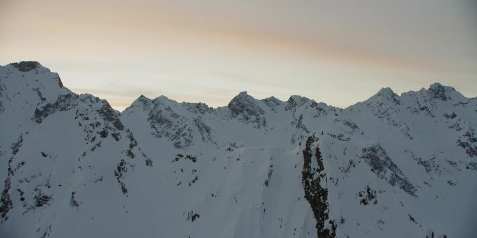 Sun sets behind snowy mountains