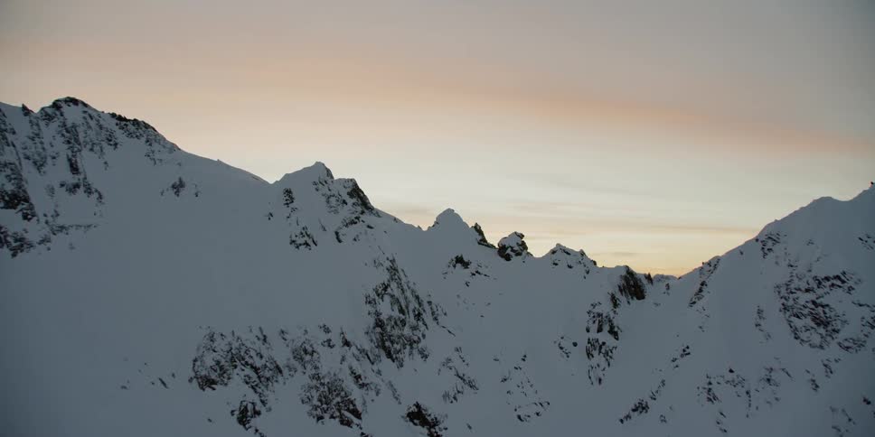 The sun sets over snowy mountains