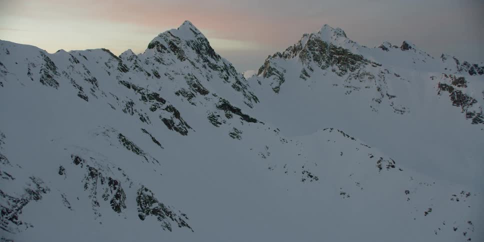 The sun sets over snowy mountains