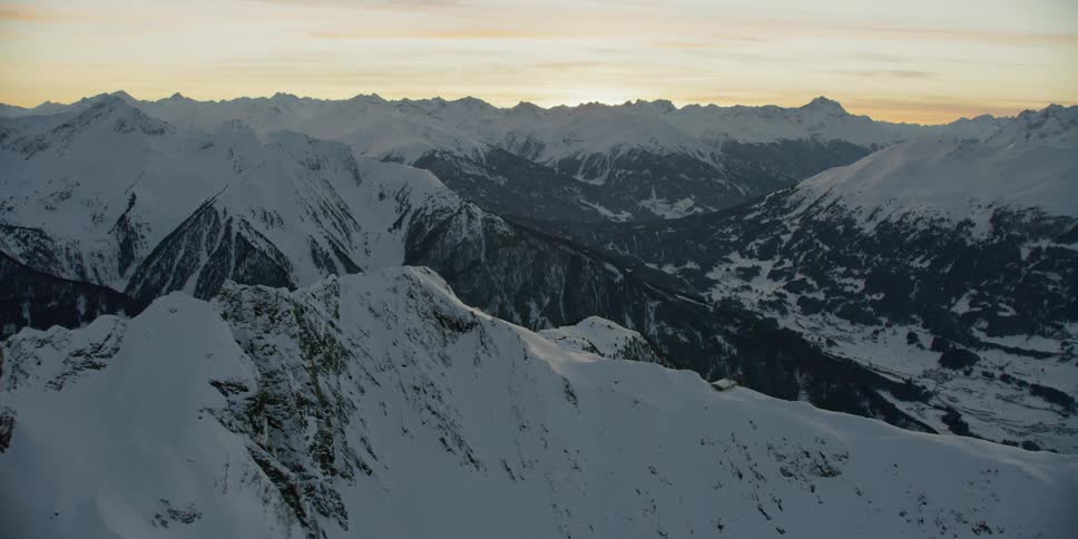 Dawn is breaking over a snow-covered mountain range