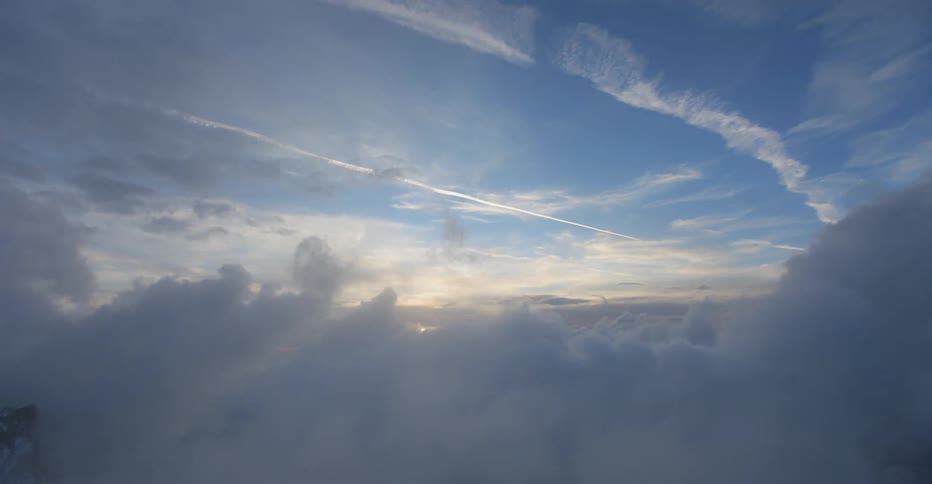 Sun shines behind puffy white clouds