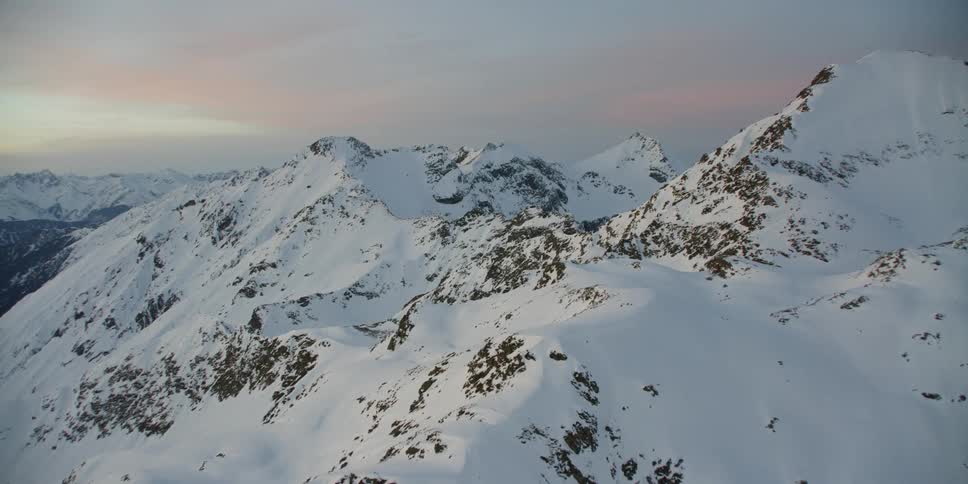 The sun sets over snowy mountains