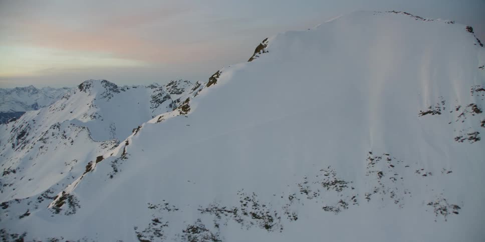 The sun sets over snowy mountains