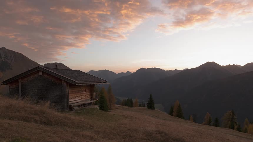 Clouds float over a mountain cabin at sunrise
