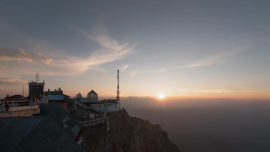Clouds float over a cliffside building at sunset