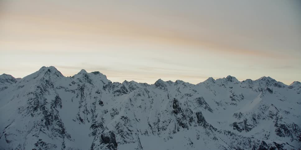 The sun sets over snowy mountains