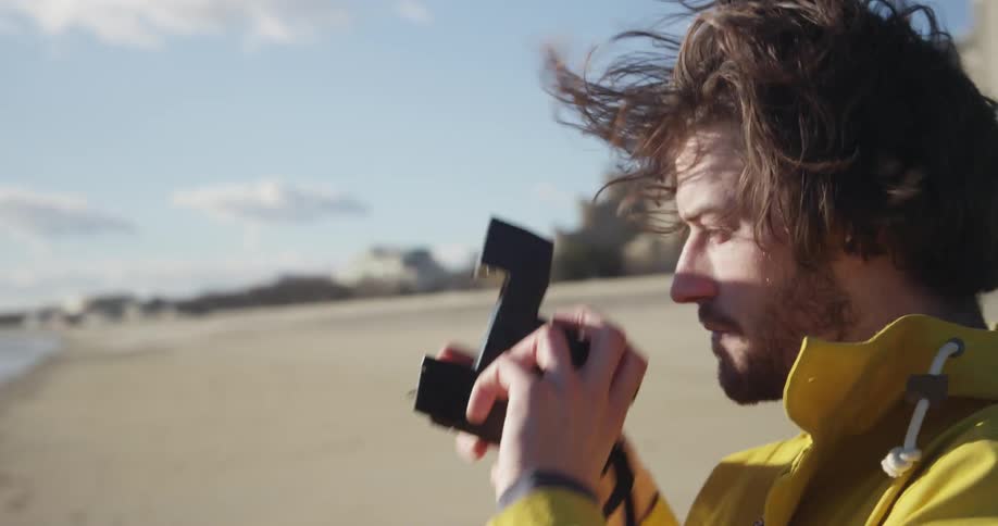 Man taking a picture of the sea with a polaroid camera