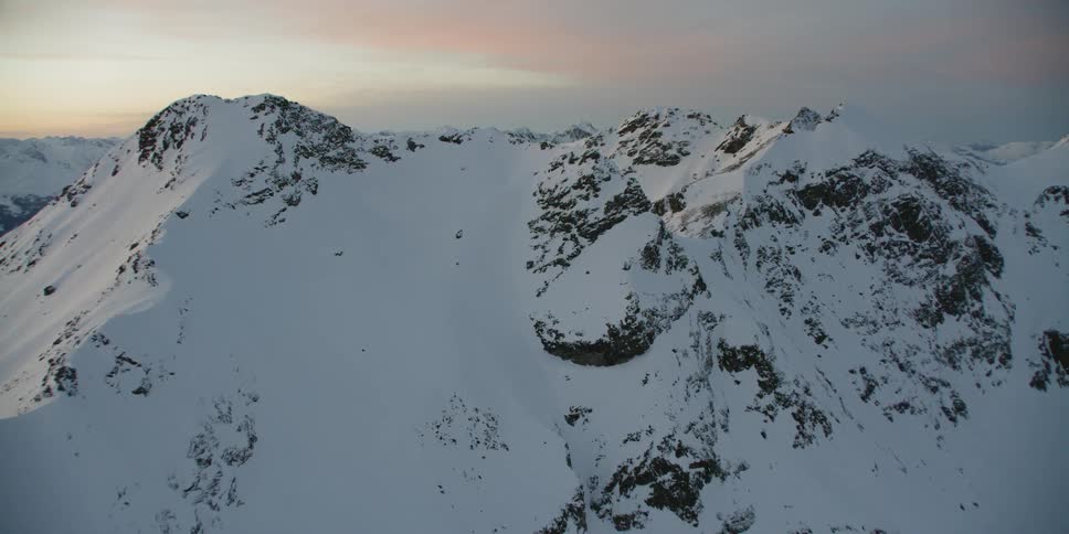 Sun sets over snowy mountains